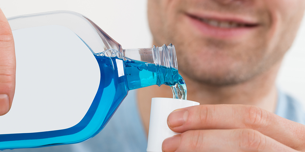 man pouring blue mouthwash to cure bad breath